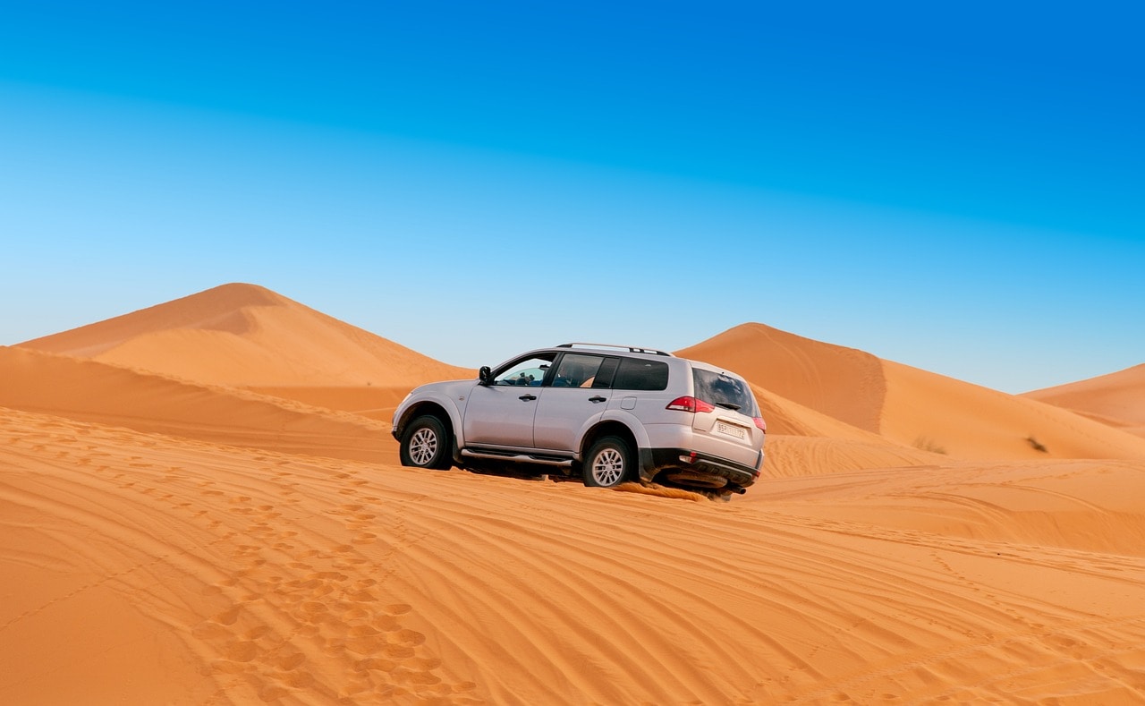 4x4 vehicle driving over golden sand dunes in Morocco’s Sahara Desert during an adventure tour.