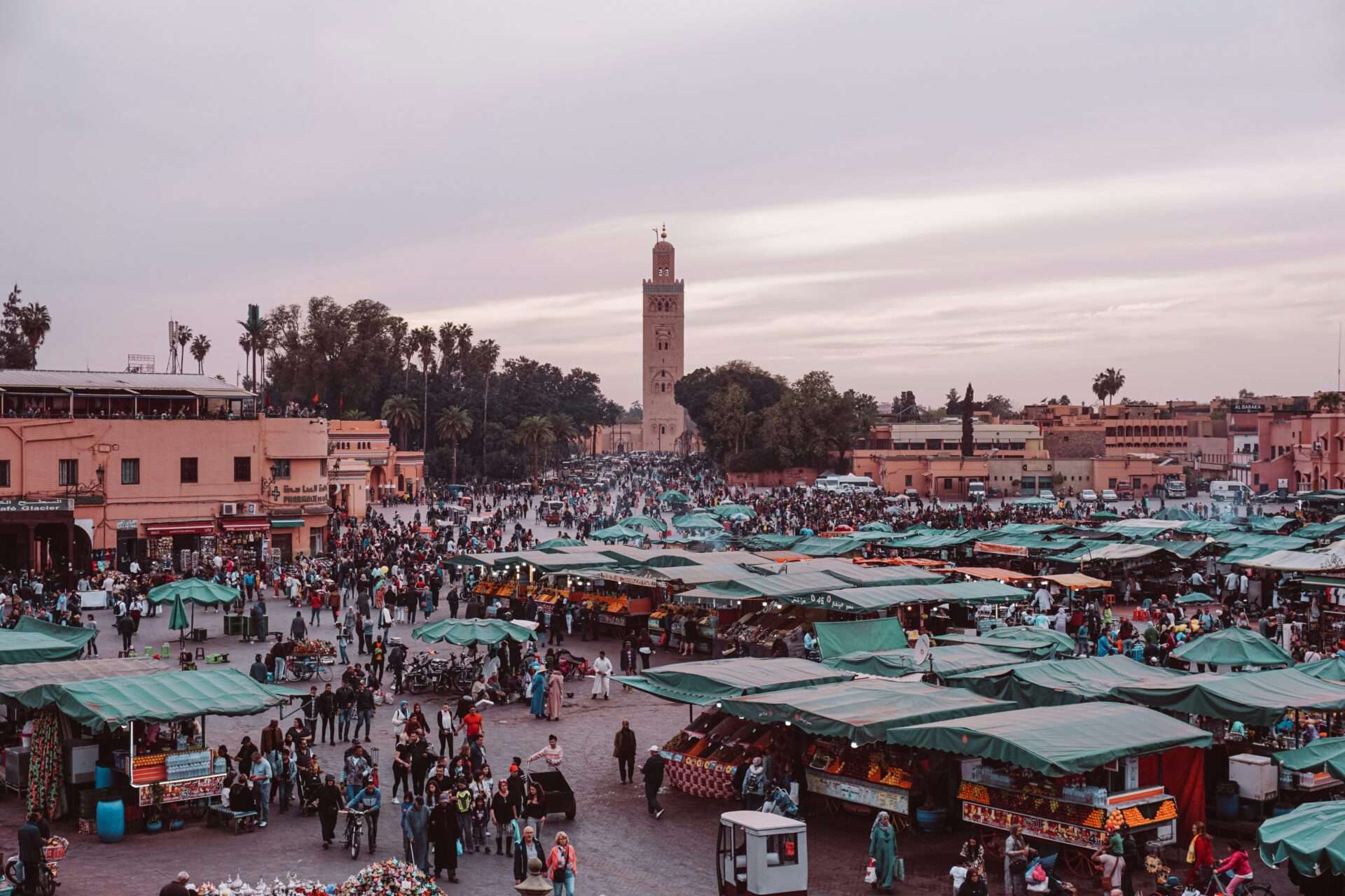 Vibrant scene at Jemaa el-Fnaa square in Marrakech, bustling with street performers, food stalls, and crowds of locals and tourists.