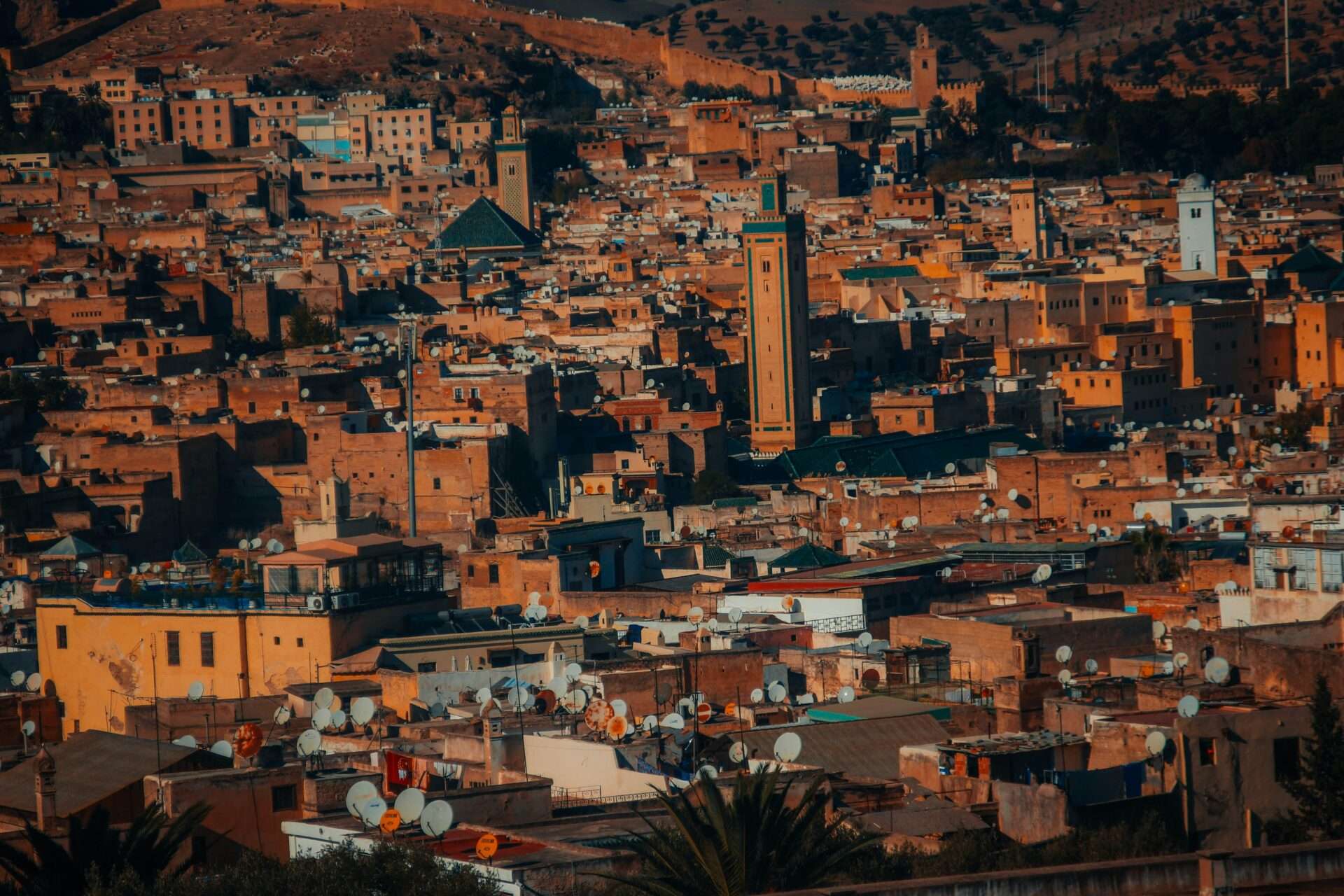 Narrow alleyway in the ancient Medina of Fes, lined with traditional shops, ornate wooden doors, and locals walking through the labyrinthine streets.