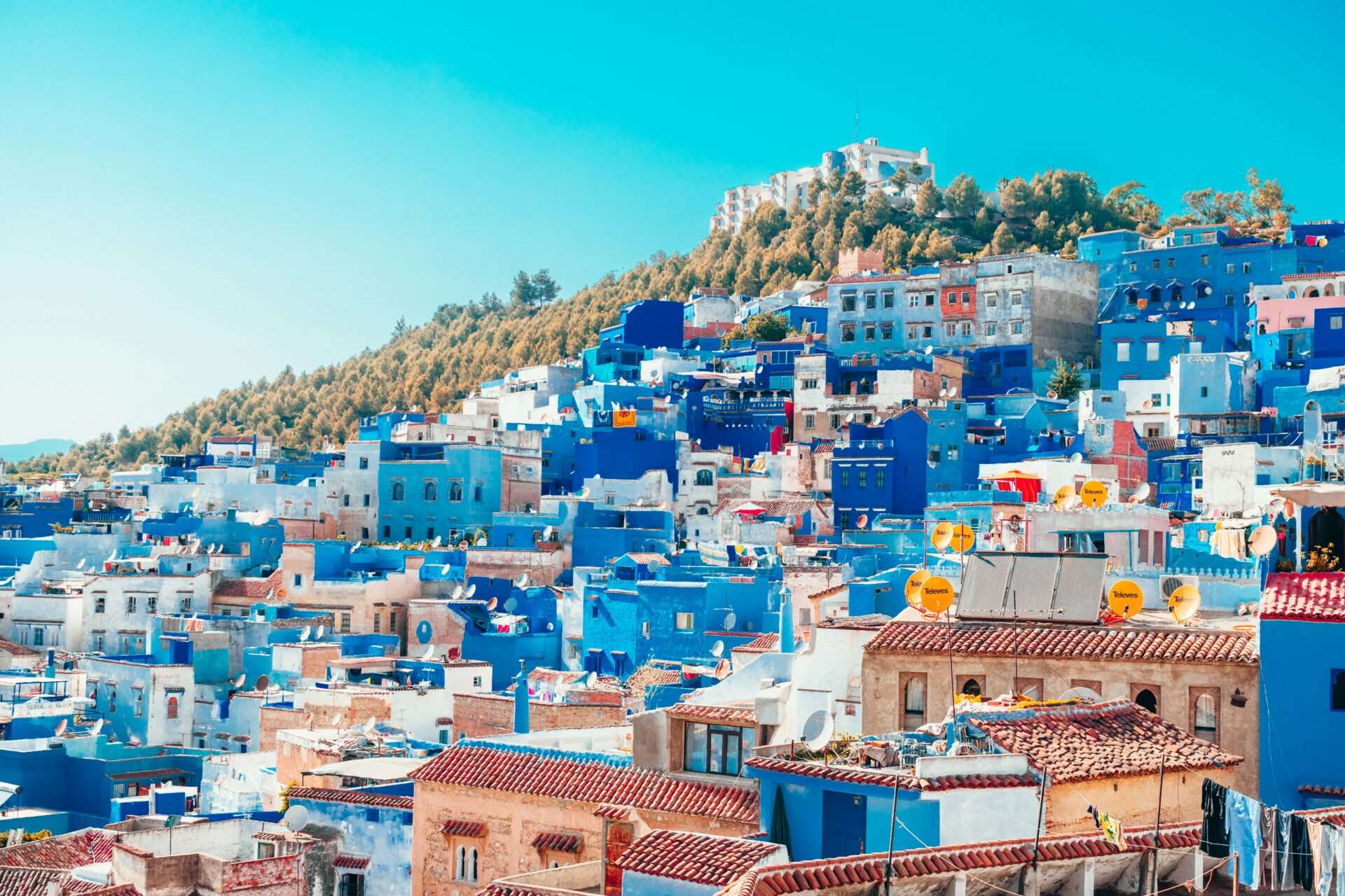 Scenic view of Chefchaouen, the Blue City of Morocco, with narrow streets, blue-washed buildings, and colorful flower pots.
