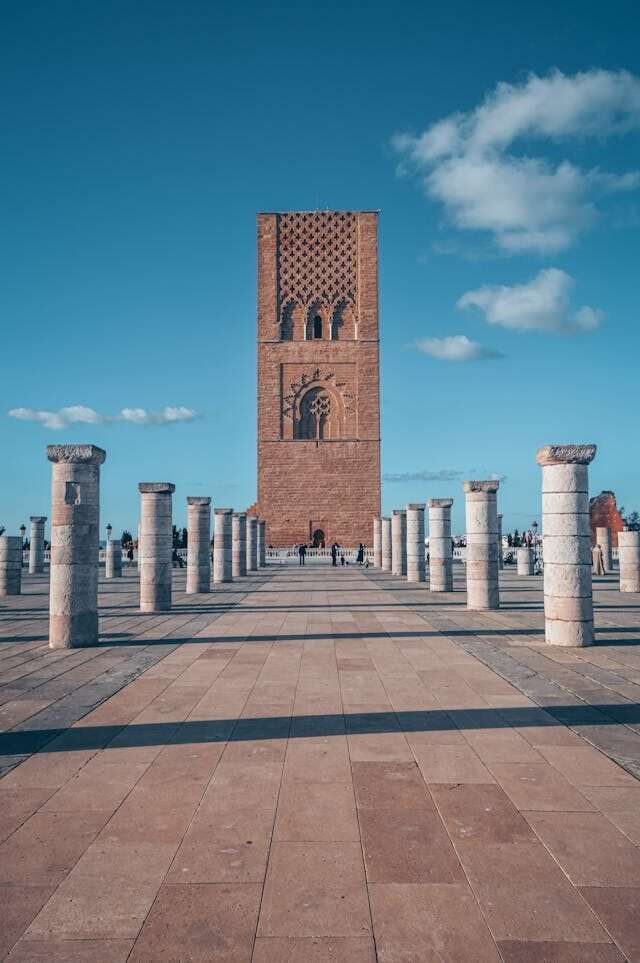 The Hassan Tower in Rabat, Morocco, a historic red sandstone minaret surrounded by rows of stone columns under a clear sky.