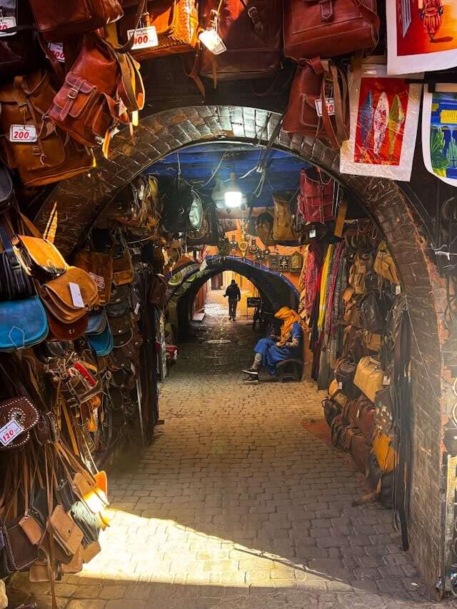 Bustling souk in the Medina of Marrakech, filled with colorful textiles, traditional lamps, spices, and local handicrafts.
